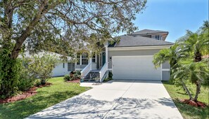 Stroll up to the front entrance of this charming home, flanked by two windows and a covered driveway leading to a garage.
