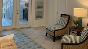 A spacious living room with a high ceiling, a ceiling fan, a staircase with white railings, and two wicker chairs with patterned cushions. - Minutes to Vanderbilt beach-1/2 mile !! Heated Pool/Spa 2650 sq ft (Naples)