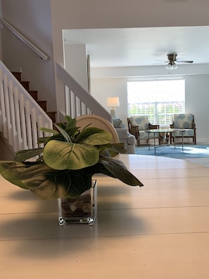 Staircase leads to an upper level, with a seating area and a large potted plant.