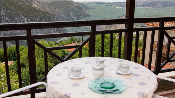 A table with a floral tablecloth, two cups, and a pitcher, set against a scenic mountain backdrop. - Apollon Stone Villa in Delphi (Delphi)