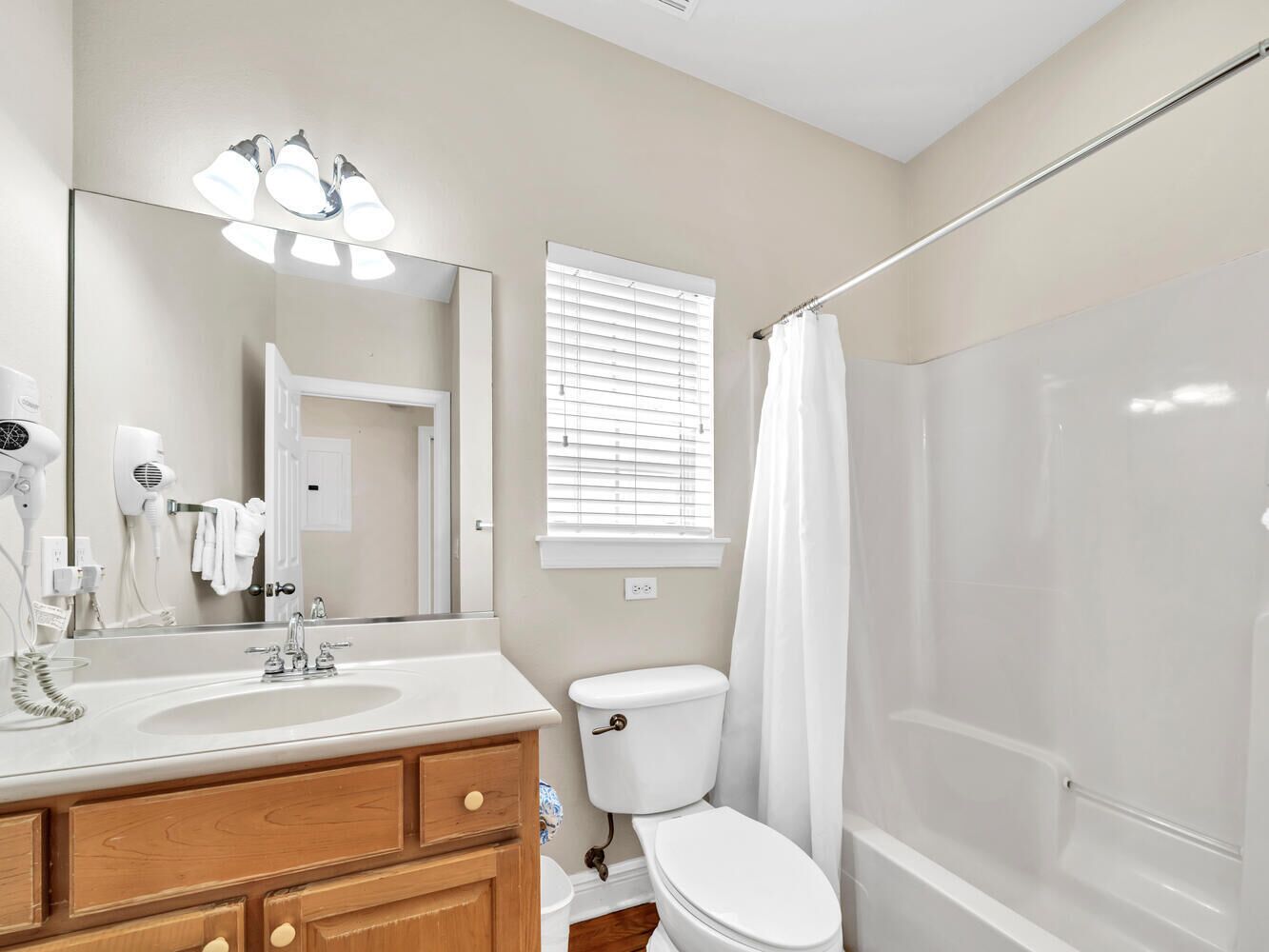 A bathroom with a sink, mirror, toilet, and shower.