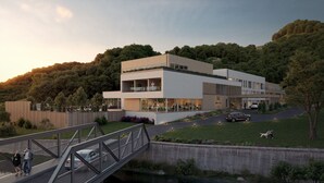 Ein modernes Hotel mit flachem Dach, großen Fenstern und einem angelegten Garten.