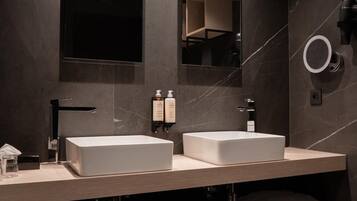 A modern bathroom with two sinks, a large mirror, and a towel rack.