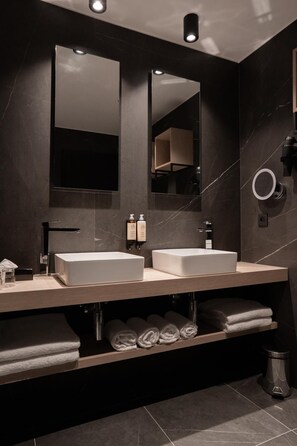 Un baño moderno con dos lavamanos, un espejo grande y un perchero para toallas.