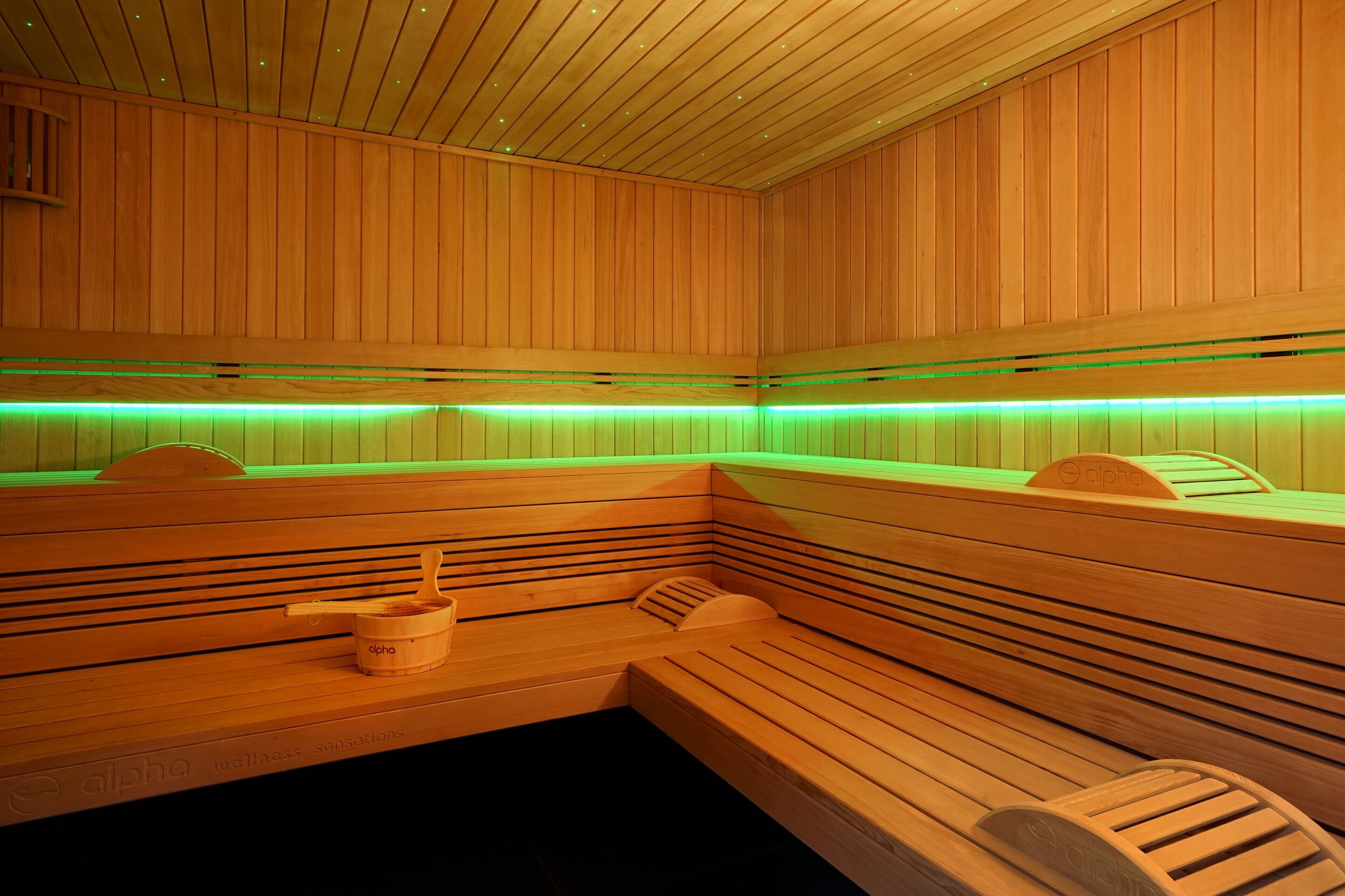 A wooden sauna with benches and a wooden bucket.
