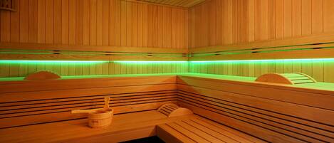 Una sauna de madera con bancos y un balde de madera.