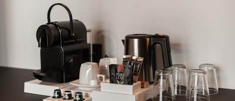 Una estación de café con cafetera, tazas y cápsulas de café sobre un soporte de madera.