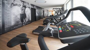 Un gimnasio con cintas de correr, equipo de ejercicio y un gran cartel motivacional en la pared.