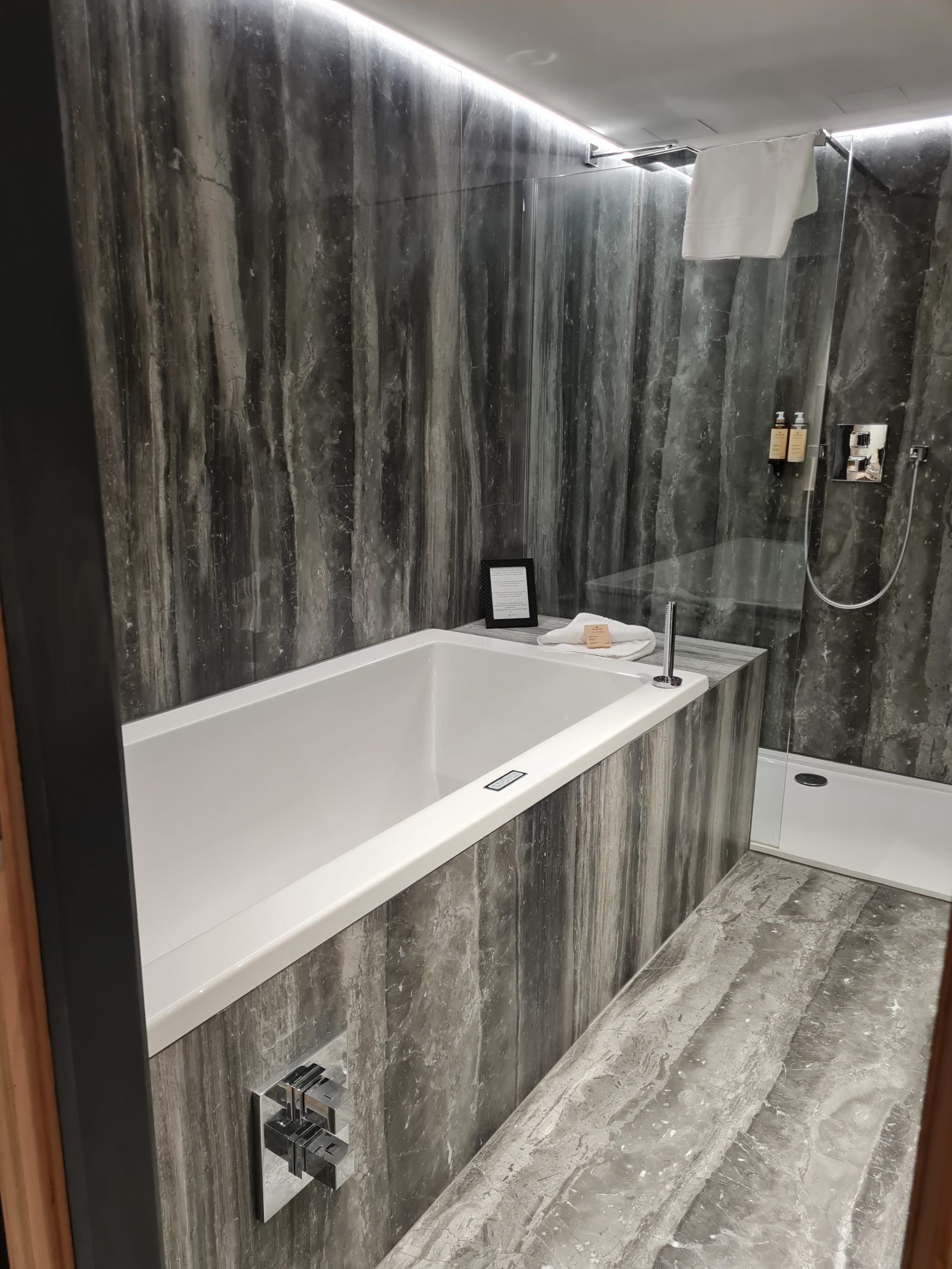A modern bathroom with a large bathtub, a shower, and a vanity with a mirror.