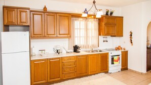 A kitchen with wooden cabinets, a white refrigerator, a stove, and a sink. - Arachova's Hilltop Delight Apartment (Distomo-Arachova-Antikyra)