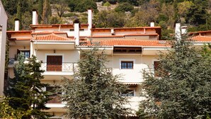 A row of buildings with red-tiled roofs and white walls, surrounded by trees. - Arachova's Hilltop Delight Apartment (Distomo-Arachova-Antikyra)