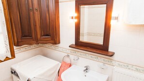 A bathroom with a wooden cabinet, a white sink, a mirror, and a towel rack. - Arachova's Hilltop Delight Apartment (Distomo-Arachova-Antikyra)