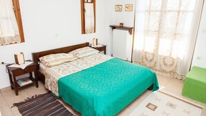 A bedroom with a bed, nightstand, and a green chair. - Arachova's Hilltop Delight Apartment (Distomo-Arachova-Antikyra)