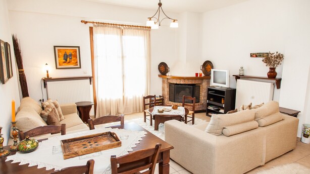 A living room with a fireplace, sofa, dining table, and chairs. - Arachova's Hilltop Delight Apartment (Distomo-Arachova-Antikyra)
