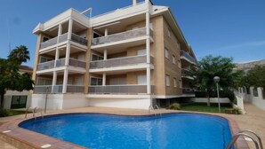 Un edificio residenziale a più piani con una piscina di fronte.