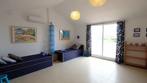 Una stanza ampia con due divani blu, un'alta credenza blu e un'ampia finestra con tende a motivi.