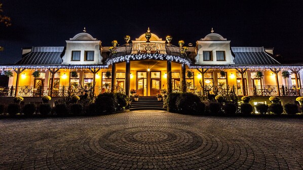 A grand hotel with a symmetrical facade, a central entrance with steps, and a decorative balustrade.
