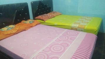 Una cama con colcha rosa y amarilla, dos almohadas y un cabecero.