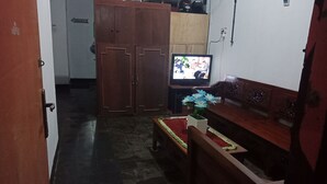 A living room with a television, a wooden cabinet, and a small table with a vase of flowers.