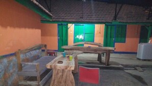 A rustic outdoor seating area with a wooden bench, a table, and a red flag.