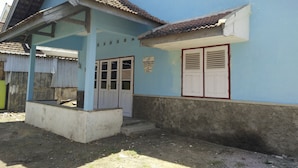 A building with a blue exterior, a tiled roof, and a covered porch area.