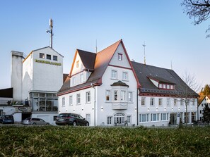 A large, white building with multiple windows and a red roof, likely a hotel or residential complex. - Hotel Das Q (Aldingen)