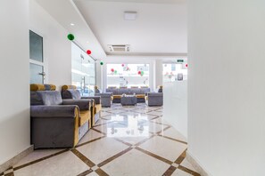 A modern lobby with a checkered floor, grey sofas, and a glass wall. - Super OYO 106 Muscat Grand Hotel Apartment (Seeb)