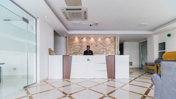 A reception area with a modern design, featuring a reception desk, a patterned wall, and a checkered floor. - Super OYO 106 Muscat Grand Hotel Apartment (Seeb)