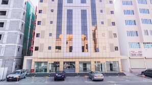 A multi-story building with a modern facade, large windows, and a visible entrance with steps leading up to it. - Super OYO 106 Muscat Grand Hotel Apartment (Seeb)