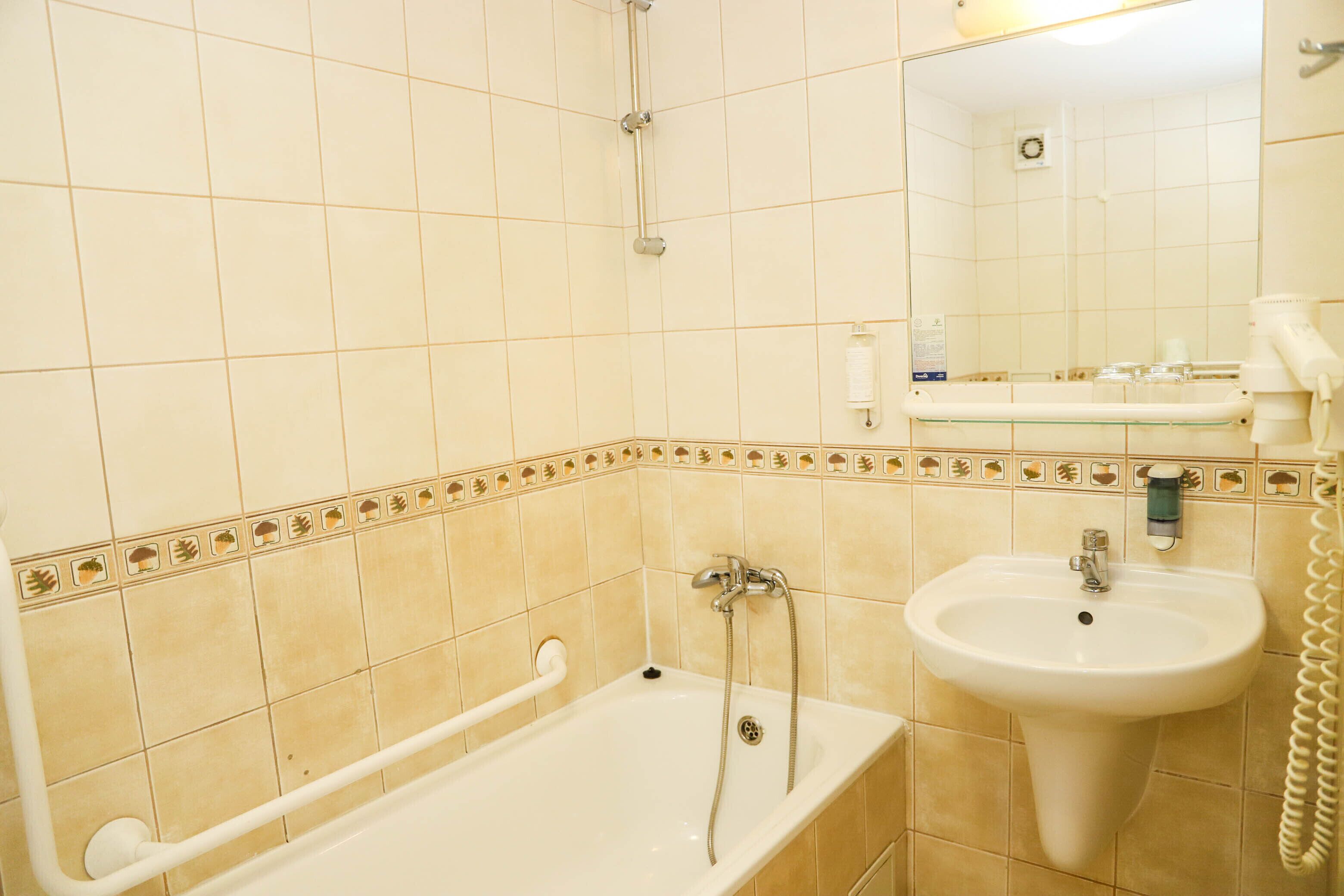 A bathroom with a bathtub, a sink, and a mirror.