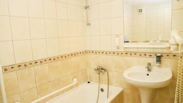 A bathroom with a bathtub, a sink, and a mirror.