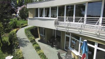 A two-story building with a balcony, outdoor seating area, and a pathway.