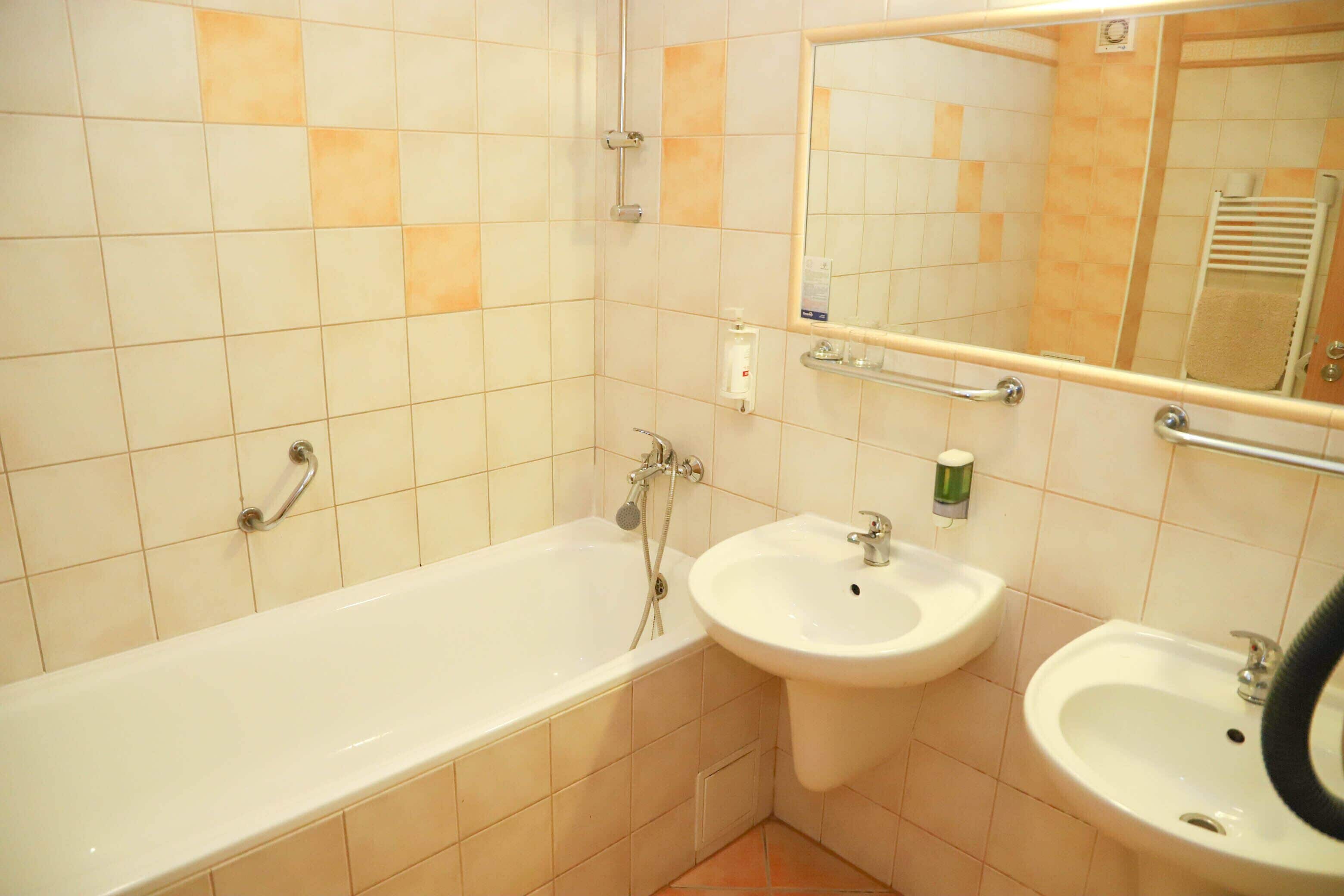 Un baño con una bañera, dos lavamanos y un espejo.
