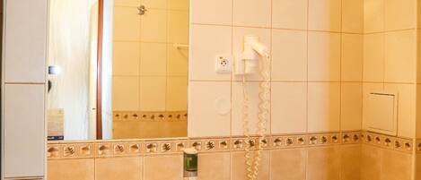 Un baño con lavamanos, inodoro y secador de pelo en la pared.