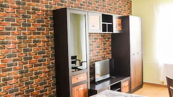 Una habitación con pared de ladrillo, un armario, una cama y una mesita.