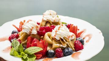 Une assiette de crêpes garnies de crème fouettée et de fruits rouges frais.