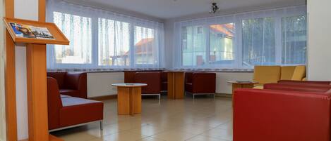 A spacious lobby with red and yellow seating, large windows, and a wooden reception desk.