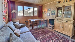 Ein gemütliches Blockhaus-Interieur mit Sofa, Esstisch, Stühlen, Fernseher und Schrank.