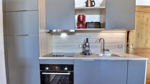 Eine kompakte Küche mit Einbauofen, Kaffeemaschine und Wasserkocher auf der Arbeitsfläche.