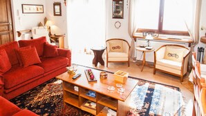 Un salon chaleureux avec un canapé rouge, une table basse en bois et un tapis à motifs.