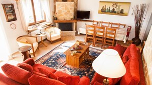Un salon chaleureux avec un canapé rouge, des chaises en bois, une table basse et une cheminée.