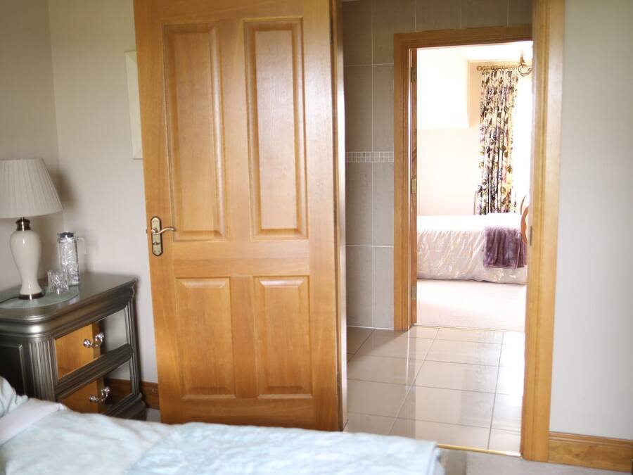 Un dormitorio con cama, cómoda, lámpara y una puerta que da a otra habitación.
