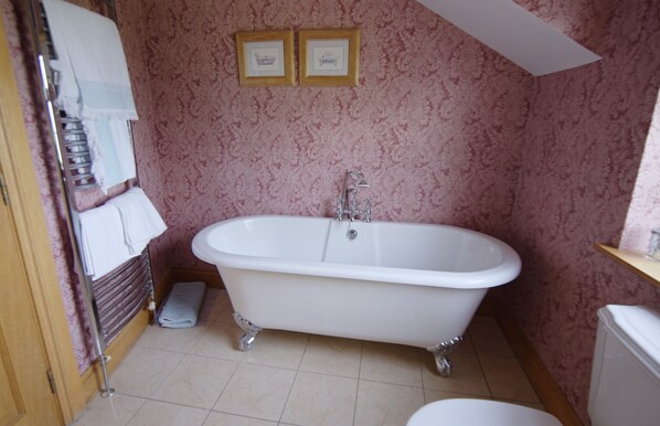 A bathroom with a clawfoot bathtub, a toilet, and a shower area.