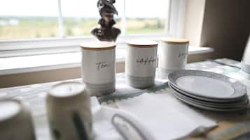 A table with three labeled containers, a stack of plates, and a window view.
