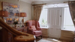 A room with a large window, a piano, a chair, and a painting on the wall. - Drum Manor (Hillsborough)