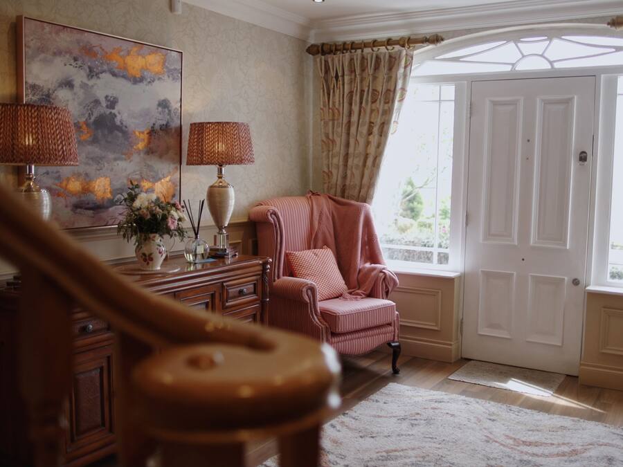 A room with a large window, a piano, a chair, and a painting on the wall.