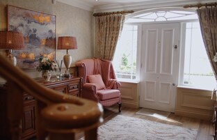 Una habitación con un gran ventanal, un piano, una silla y un cuadro en la pared.