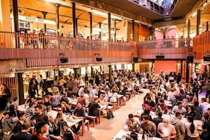 A spacious indoor venue with multiple levels, featuring a central open area surrounded by tables and chairs where people are seated. - F5G sleeps 3 Convenient 1 bed sofabed wifi (London)