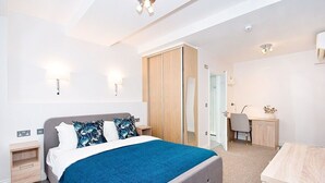 A modern bedroom with a bed, bedside tables, a desk, and a wardrobe.