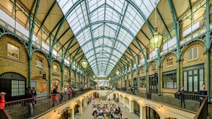 A spacious indoor market with a high, glass-roofed ceiling and multiple levels of walkways.